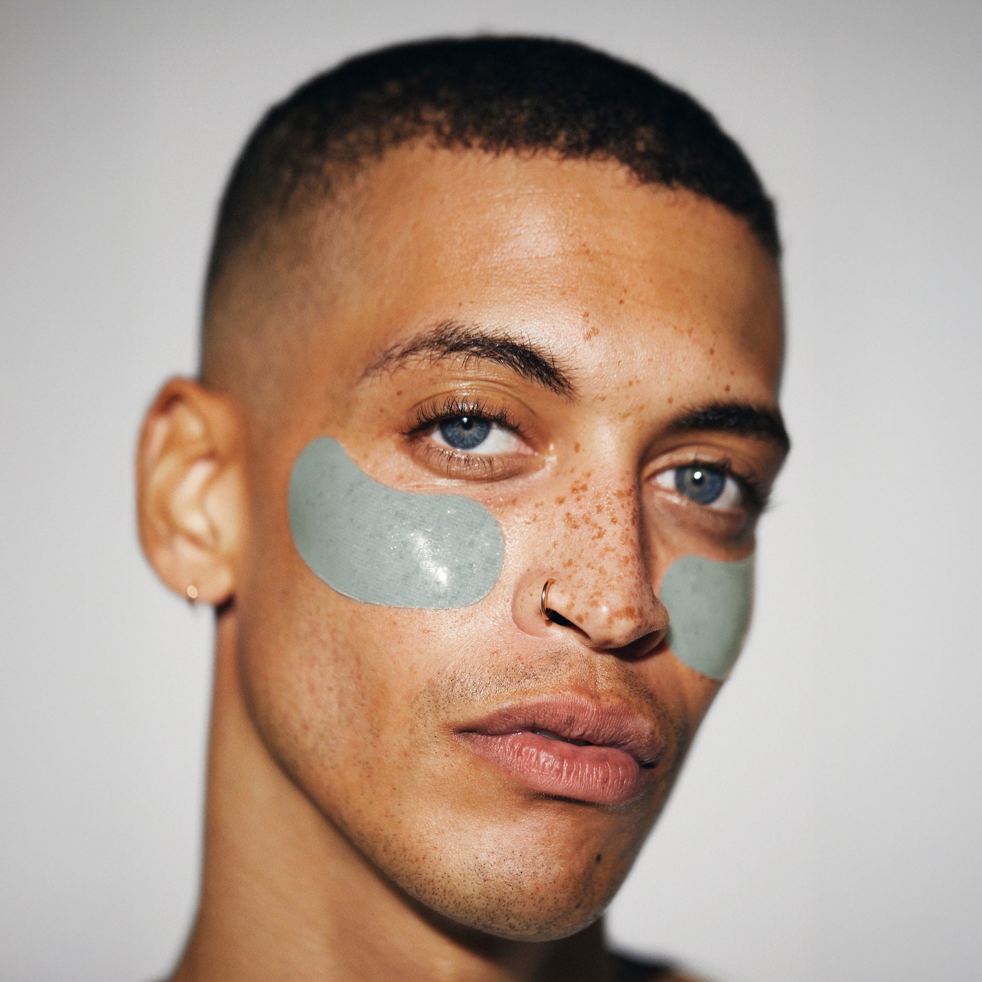 Male model facing forward with translucent, LOOPS Hydrogel under eye mask on.