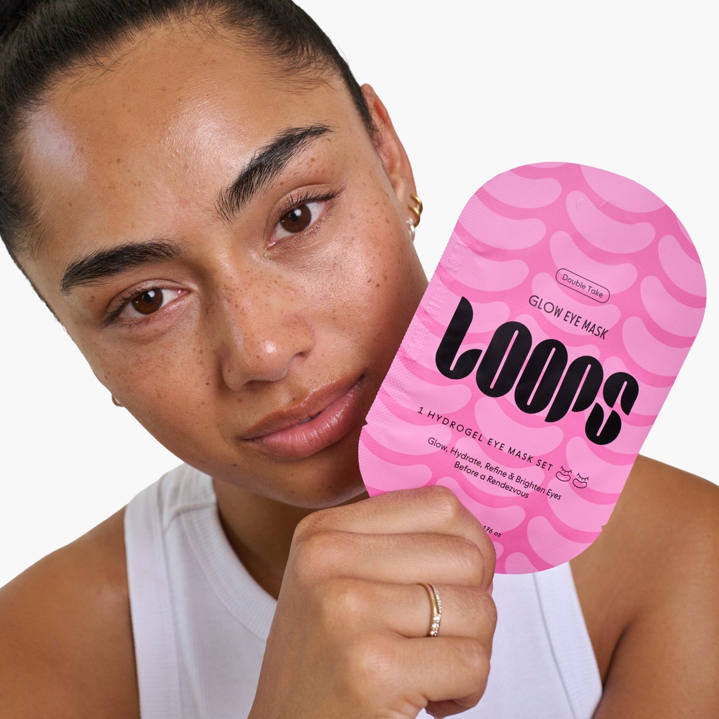 Woman holding a pink 'LOOPS' eye mask against a white background