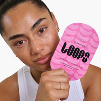 Woman holding a pink 'LOOPS' eye mask against a white background