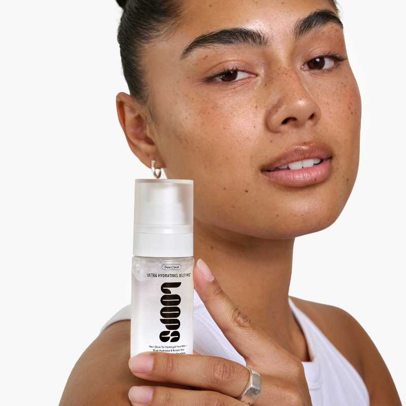 Woman holding a Loops skincare bottle against a white background