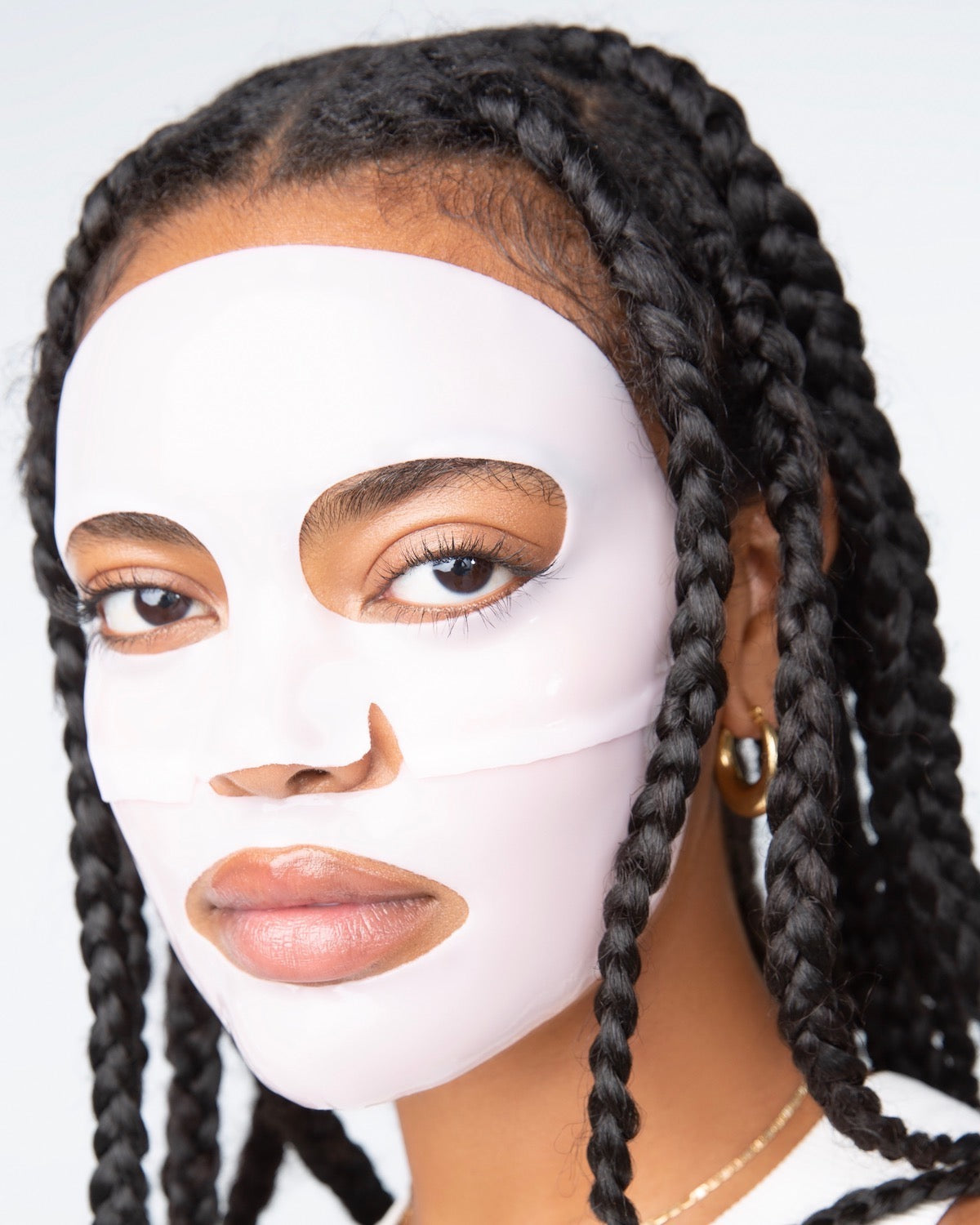 Female model facing forward with a pinkish-white, 2-piece LOOPS Hydrogel face mask on.